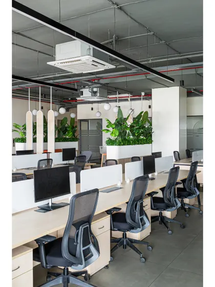 Another view of the open-plan workstation area, highlighting the exposed ducting and services on the ceiling, painted to blend in. The design is honest and functional, celebrating the structural elements of the building.