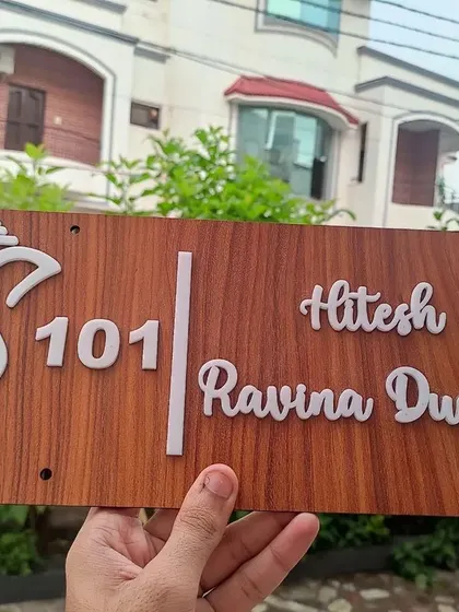 Welcome guests with a custom wooden door nameplate. This design features a traditional Ganesha motif alongside the family names and flat number, adding a personal and auspicious touch to your home's entrance.