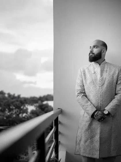 A groom's portrait in black and white on a balcony overlooking a serene landscape. His thoughtful gaze into the distance speaks of the future he is about to begin.