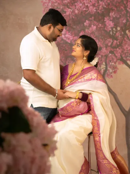 A beautiful shot of an expecting couple holding hands and looking at each other, captured during their traditional-themed maternity session in the studio.