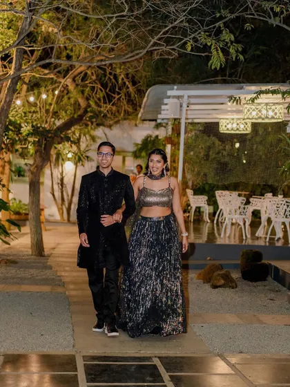 A couple makes a grand entrance at their evening cocktail party. The path is lit, and the trees provide a natural canopy for this stylish and celebratory moment.