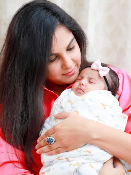 A mother's love. She holds her sleeping, swaddled daughter close, a picture of pure grace and affection.