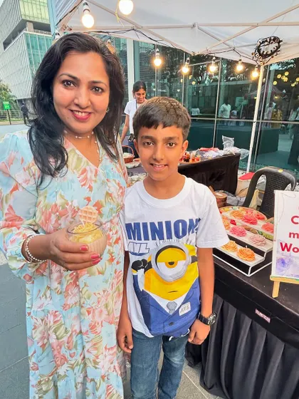 A mother and son pose with the candle they made together at our live booth, a great family-friendly activity.