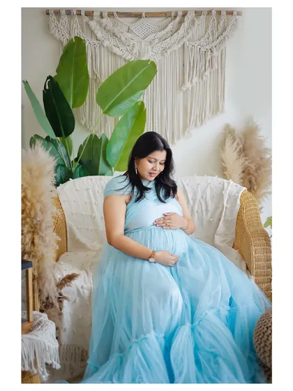 A peaceful portrait of a mother-to-be in a light blue gown, seated in our boho-themed corner. The natural elements like pampas grass add a soft, organic touch.