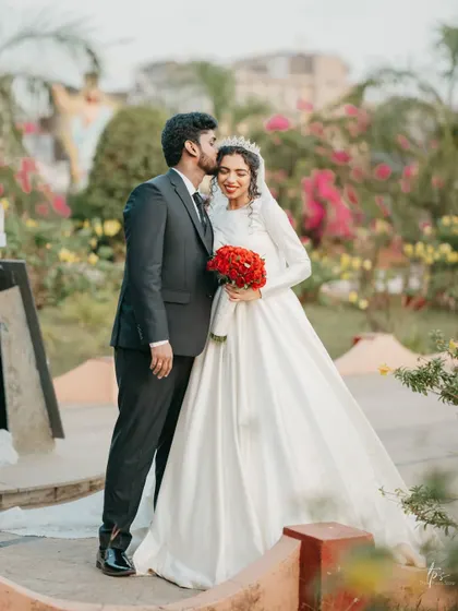 A sweet kiss on the forehead. A romantic moment between the couple in a beautiful garden setting.
