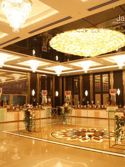 A wide view of one of our luxurious banquet hall setups. The grand chandeliers and reflective flooring complement our meticulously arranged food stations, creating an atmosphere of pure opulence.