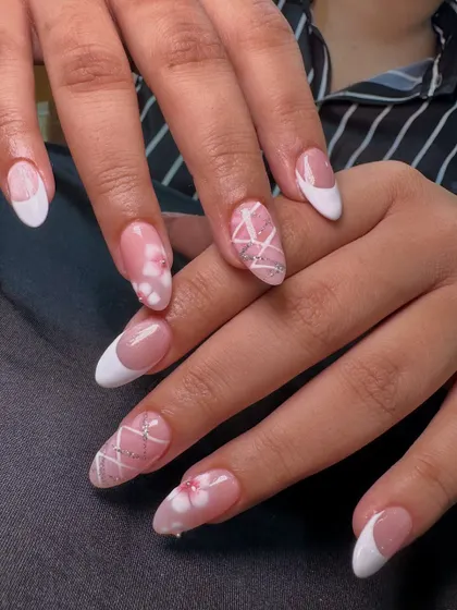 This is such a cute and dreamy set. It combines a classic white French manicure with accent nails featuring 3D floral details and a delicate crisscross glitter pattern.