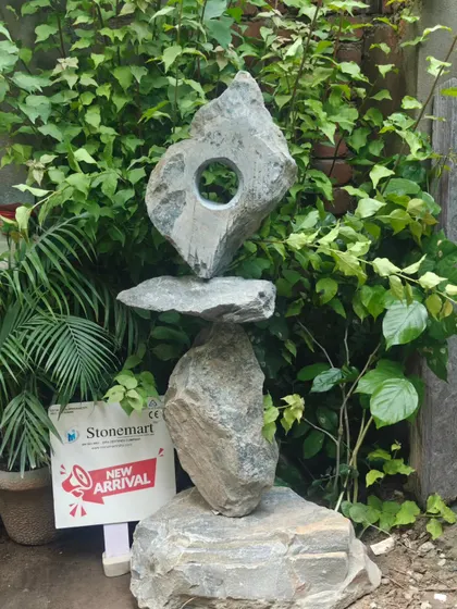 The unique, balancing design of this large abstract sculpture makes it a captivating addition to any landscape. It is hand-carved from natural stone for an authentic, rustic feel.