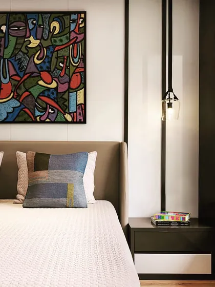 The second apartment features a more modern and art-focused design, with a bold painting serving as the centerpiece of the bedroom.