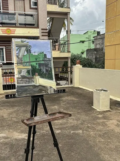 The finished acrylic painting of a green building, seen from a rooftop, perfectly matching the real-life view.