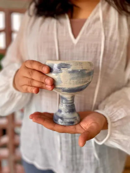 Mansa holding her hand-painted goblet, a piece that beautifully represents her artistic journey.