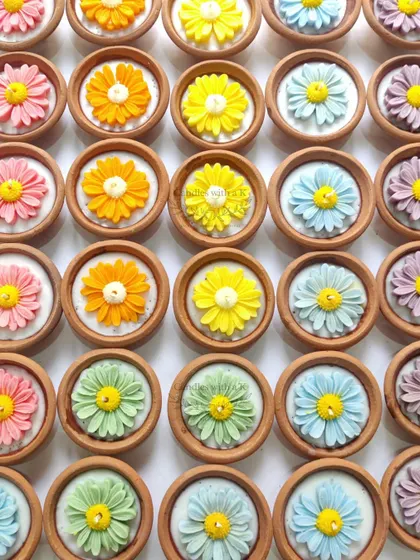 A rainbow of daisy clay pot candles, showcasing the variety of colors available for festive orders.