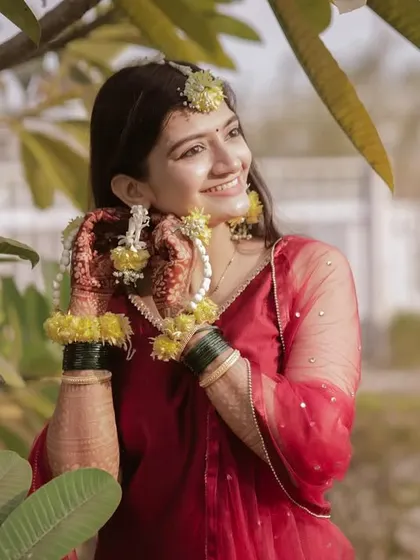 A beautiful bride enjoying a quiet moment during her Haldi ceremony, adorned with floral jewelry.