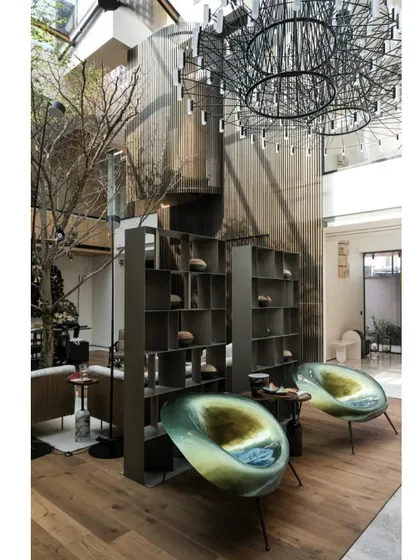 A stunning interior from the retrofitted home, featuring a double-height space with a dramatic chandelier and unique, artistic seating. The project masterfully blends bold new elements with the original structure.