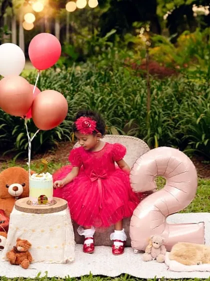 A candid moment during a second birthday celebration. This little girl is enjoying her special day in a beautiful outdoor setting, creating a cherished memory.