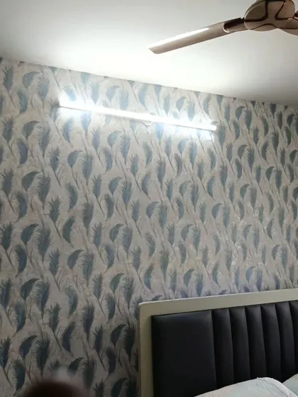 A bedroom wall featuring a delicate feather pattern in shades of blue and grey. The design is light and airy, creating a calm and peaceful ambiance.