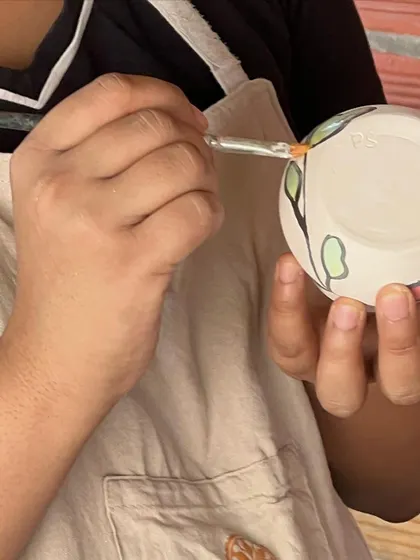 A student carefully applying underglaze to their pottery. This is where they add color and personality to their creations.
