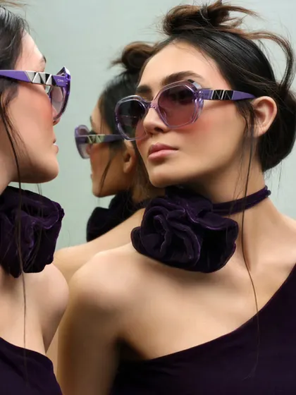 This image for IDEE Eyewear plays with reflections to create a captivating and slightly surreal effect. The styling and pose are designed to highlight the unique shape and color of the frames.