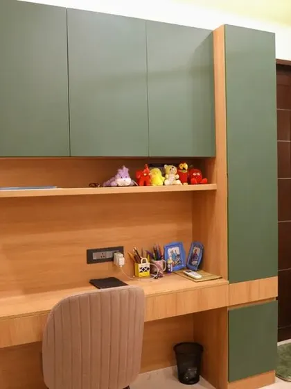 A custom study unit in the Velachery apartment, with a spacious desk, overhead cabinets in green, and an attached dressing mirror.