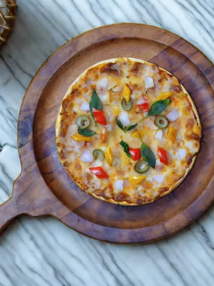A freshly baked vegetarian pizza served on a rustic wooden board. My live pizza stations allow for a variety of toppings to suit every guest's preference.