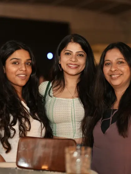 A group of three friends smiling for the camera, enjoying their night out.