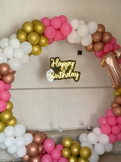 The neon "Happy Birthday" sign adds a modern, glowing touch to the center of the balloon ring.