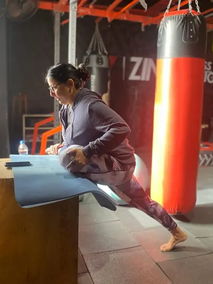 This pigeon pose stretch is being performed on a plyo box to increase the intensity. It's an excellent way to release tight hips and improve flexibility, which is crucial for overall mobility.