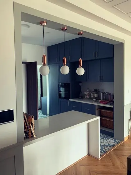 Work in progress! A sneak peek of a bold blue kitchen with a white countertop island and stylish copper-accented pendant lights.