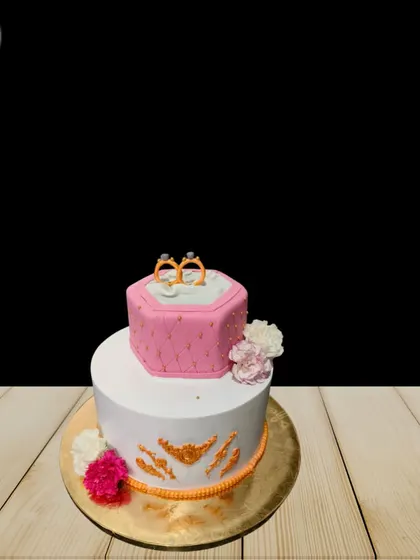 A simple yet elegant two-tier engagement cake. The top tier is a quilted pink ring box, while the bottom tier features delicate gold detailing, perfect for an intimate celebration.