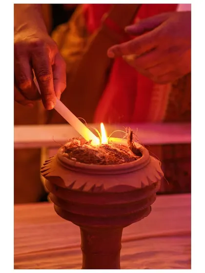 A hand lights the coconut husk and incense inside a dhunuchi pot, the beginning of the evening ritual dance.
