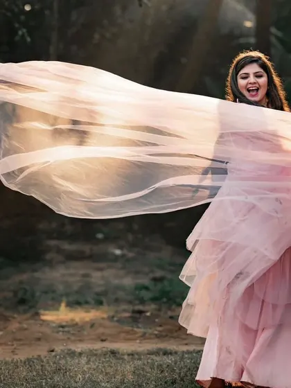 A joyful, candid moment showing the bride playing with the flowing net fabric. This gown is all about light, air, and effortless beauty.