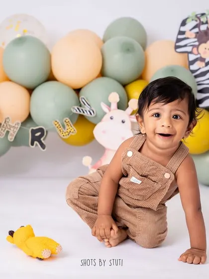 Before the cake, we always take some time for classic portraits. This little one's happy crawl in his adorable corduroy overalls shows off his playful personality against the zoo-themed backdrop.