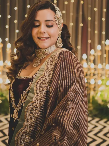 The bride's smile lights up the room. Her deep-colored velvet outfit and sparkling jewelry are perfect for a glamorous reception night.
