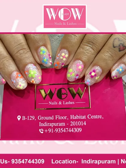A fun and colorful design on short, square extensions. This look features a glittery base with multi-colored floral polka dots, creating a playful and happy vibe.
