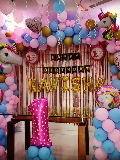 A first birthday party with a "Baby Girl" unicorn theme. This dense balloon arrangement in pink and blue features multiple unicorn head foil balloons and a personalized name banner for "KAVISHA".