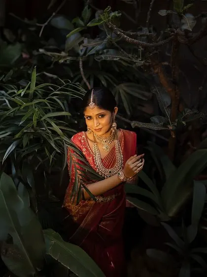 A bride surrounded by lush greenery, her face illuminated by a soft, focused light. This portrait is intimate and highlights her beauty in a natural, serene setting.