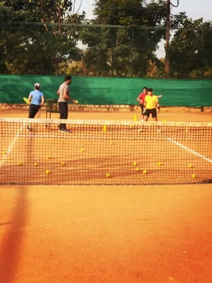 A group of students practices their strokes from the baseline. Repetitive drills are key to building the muscle memory needed for consistent shots.