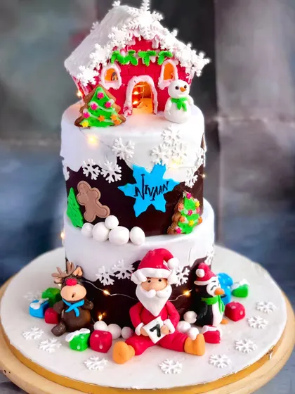 A tiered Christmas cake carries Santa, snowflakes and a snowy house detail... our festive design gathers the seasonal characters together.