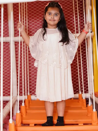 A young girl poses on the rope bridge, ready for her next adventure in the play gym.