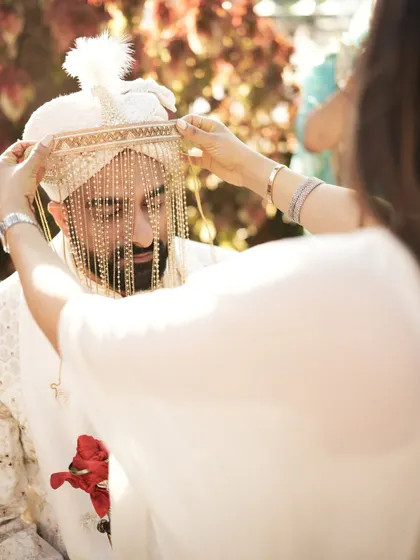 A mother's loving hands adjusting the groom's sehra, a beautiful, sentimental moment before the ceremony.