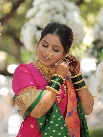 The bride adjusts her earring, showing a close-up of her glowing makeup and traditional gold jewelry.