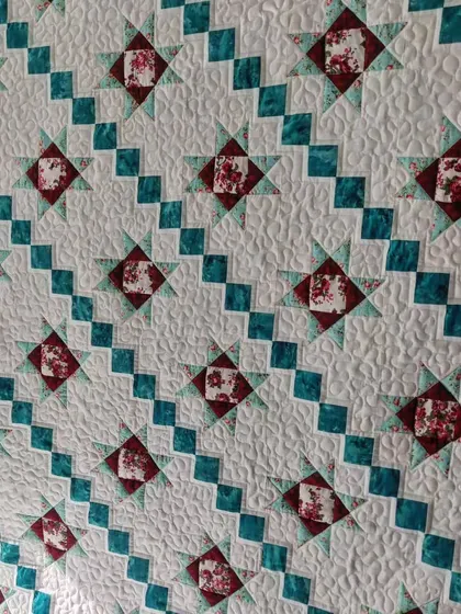 A detail shot of a star quilt, showing the stippling quilting in the background.