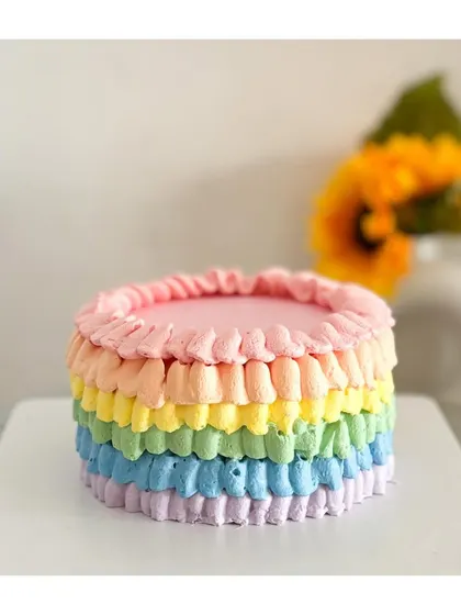 A colorful smash cake for a very special first birthday. This rainbow-themed cake is frosted with light whipped cream, making it baby-friendly and perfect for those memorable photos.