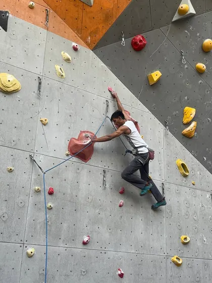 A climber clips the rope into a quickdraw on our outdoor wall. Lead climbing requires both physical strength and mental focus to manage the rope as you ascend.