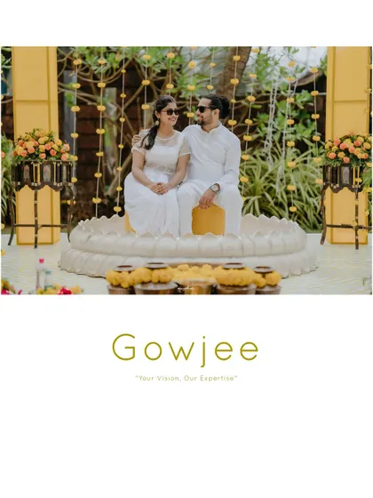 The couple posing for a photo at their Haldi ceremony, seated on a unique lotus-shaped platform.
