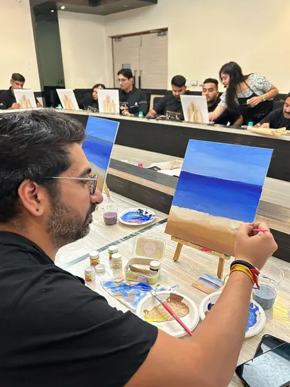 A participant in a corporate workshop, fully engaged in painting his beach scene.