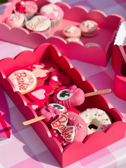 A close-up of the adorable Barbie-themed sweets, including custom cookies, cake pops, and donuts, all decorated in shades of pink.