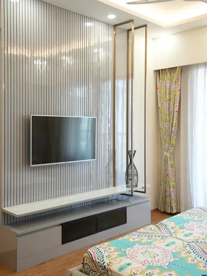 This bedroom TV unit stands out with its vertical-striped panel backdrop and suspended marble-finish shelf, while a metallic frame detail adds a contemporary flair.