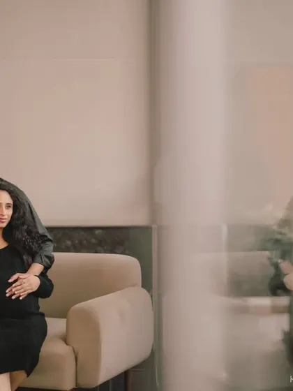 A sophisticated indoor portrait of an expecting couple. The composition and their poses create a modern and elegant feel.