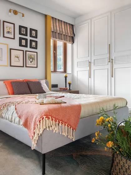 We used a variety of textures and warm colors in this bedroom to create a cozy and inviting atmosphere. A gallery wall of botanical prints adds a personal touch, while the paneled wardrobe provides ample storage with a classic aesthetic.